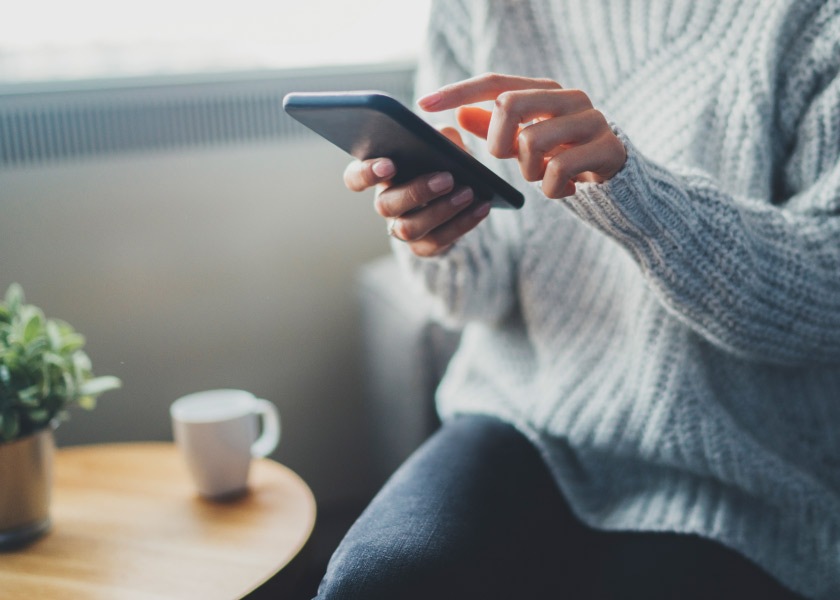 Person in cozy sweater holding phone