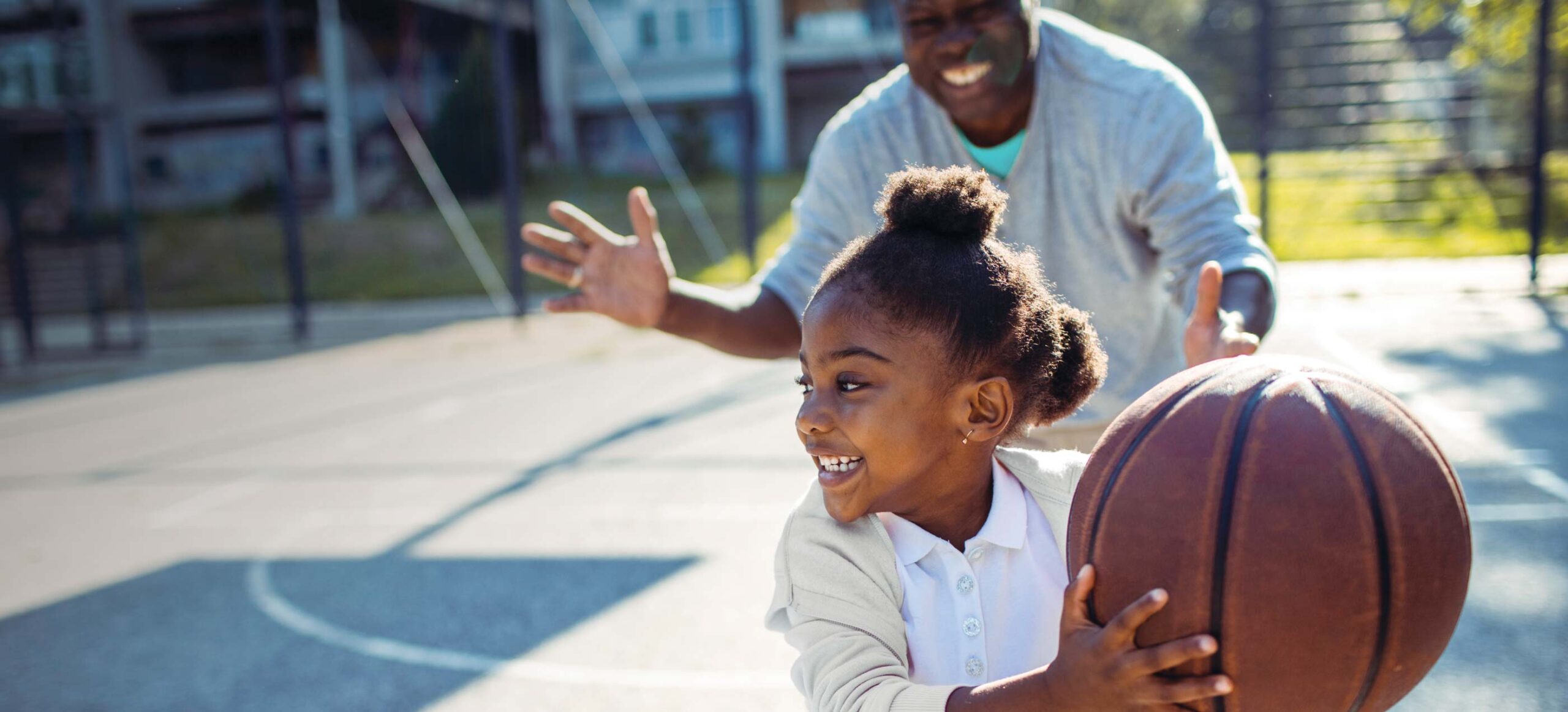 Dad and daughter playing basketball outdoors